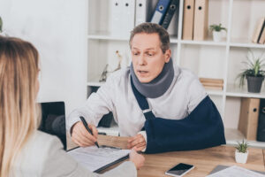 Injured man with neck collar and arm bandage filing claims