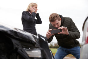 Driver taking photo on damage car.