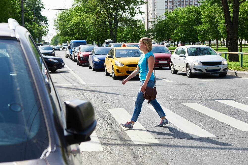 Woman walking in pedestrian lane while car is passing.