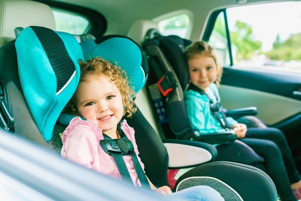 Happy children sitting in booster seat at the back.