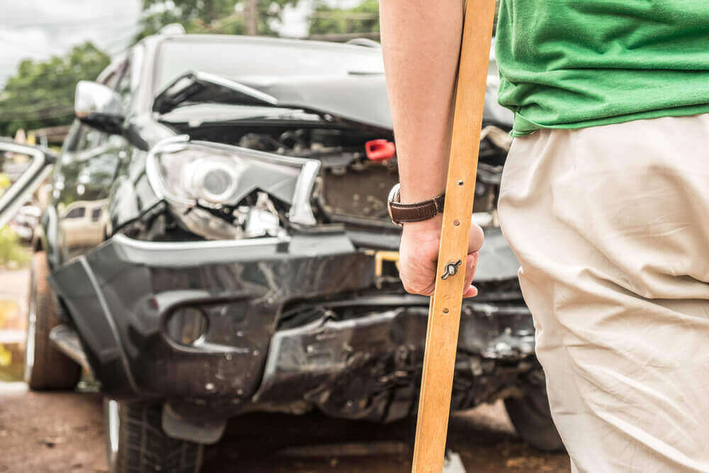 Injured driver looking at the car damage from accident.