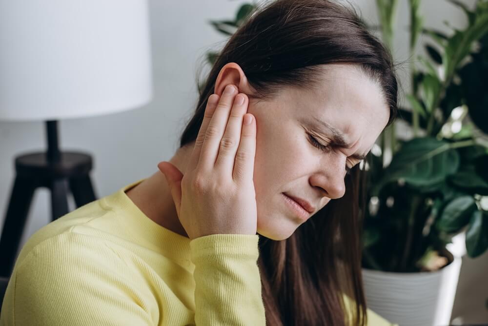 Middle-aged lady experiencing tinnitus or ringing in the ears.